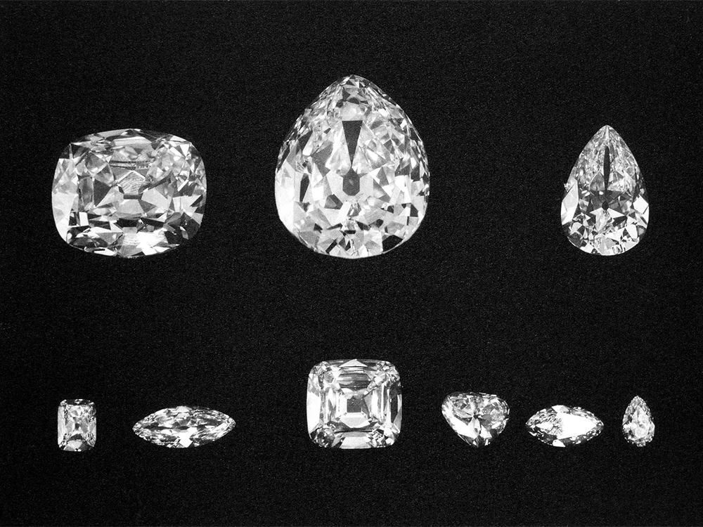 The nine major polished Cullinan diamonds arranged in two rows against a black background: a cushion, a large pear and a smaller pear above, and six smaller stones below
