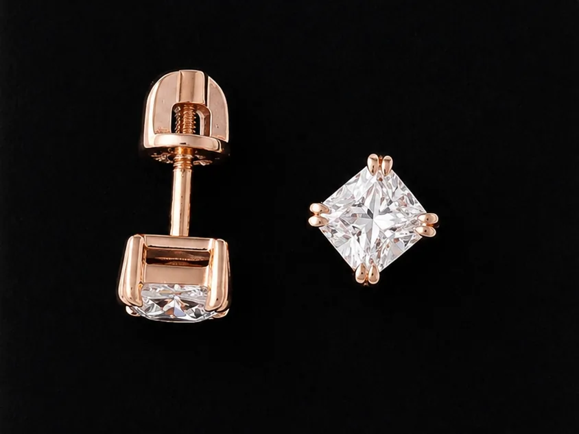 One earring face-up and the other lying on its side on black velvet, showing the post and the screw fitting behind the stone
