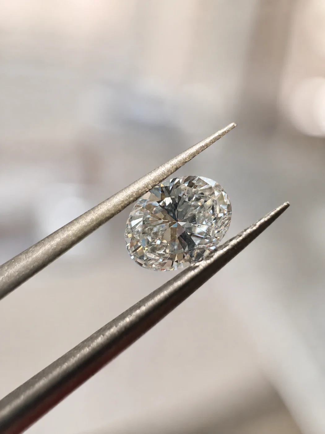A 0.23 carat oval diamond held in tweezers