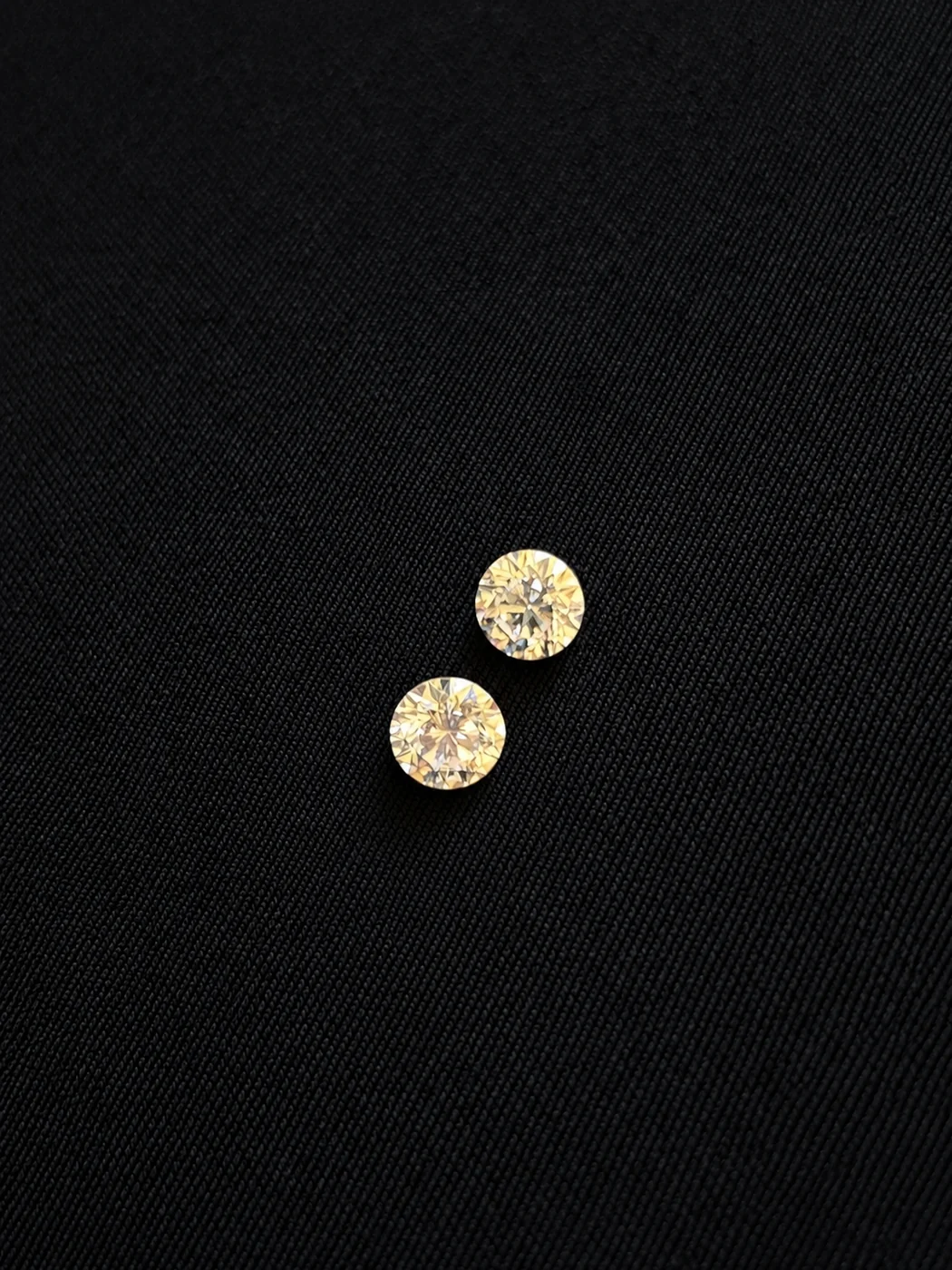 Two matched 0.40 carat round brilliant diamonds on black fabric