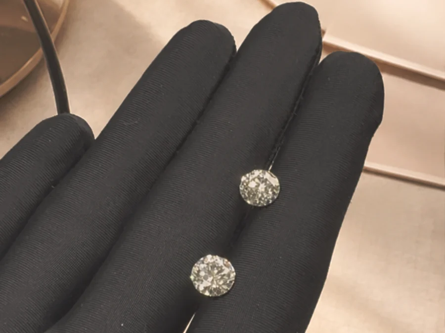 Deux diamants taille brillant comparés côte à côte sur une main gantée