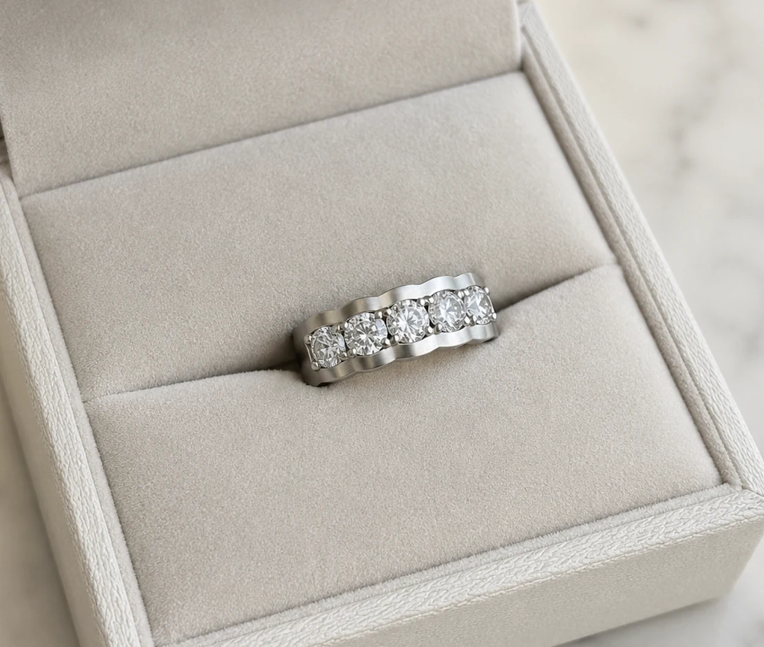 L’alliance cinq pierres terminée dans son écrin, cinq diamants taille brillant sertis en ligne sur une monture en métal blanc