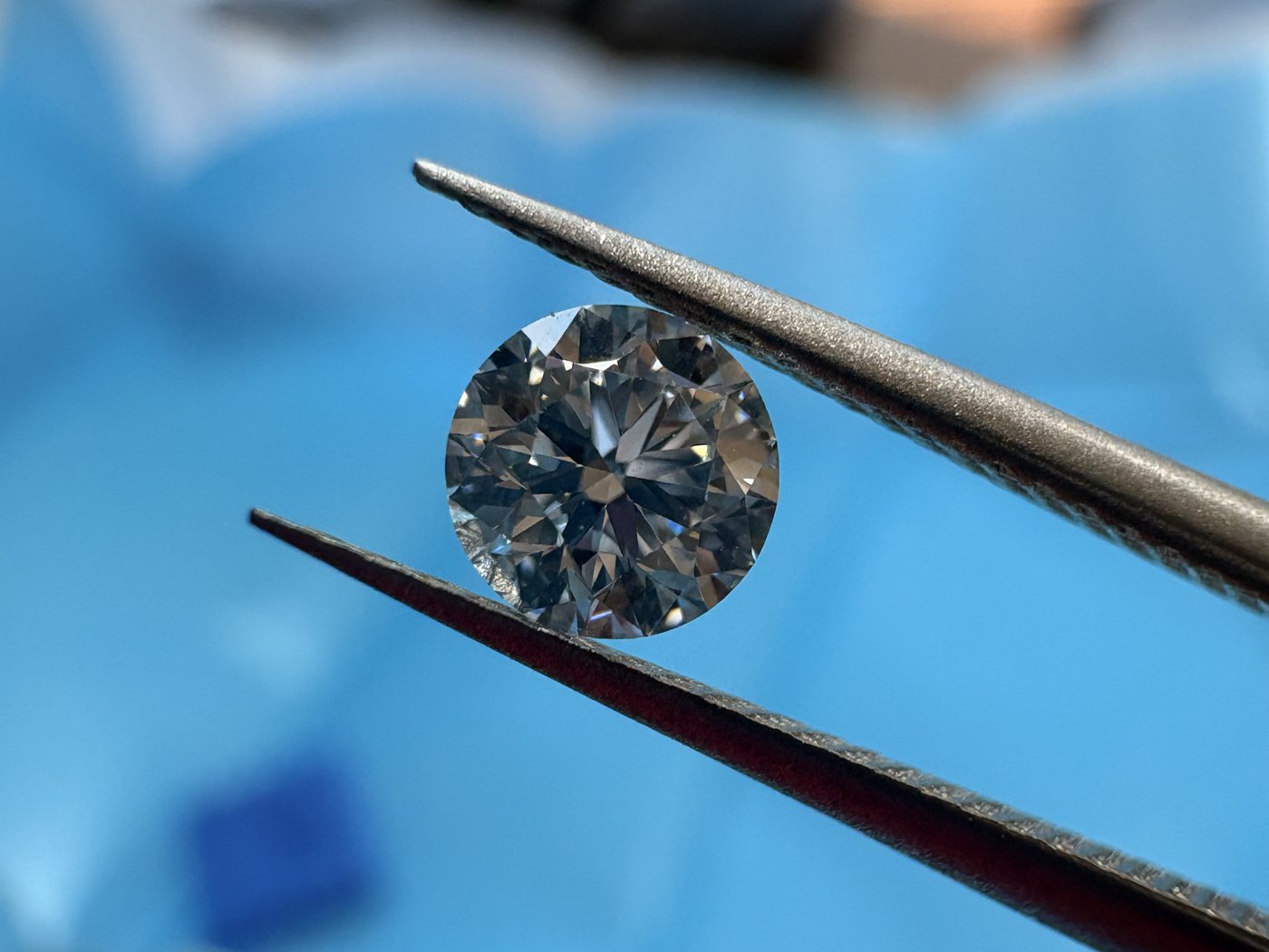 A round brilliant diamond held in tweezers and examined in daylight